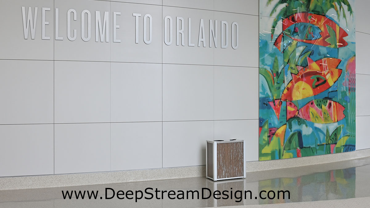 DeepStream modern combination trash and recycling bin in the welcome area of the Orlando Intermodal Center with a tropical mural behind